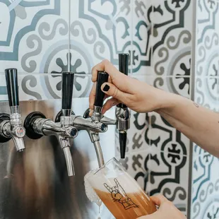 a person filling a beer from a tap