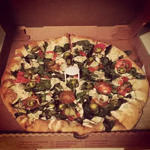White pizza with jalapeños artichokes spinach tomatoes and vegan cheese