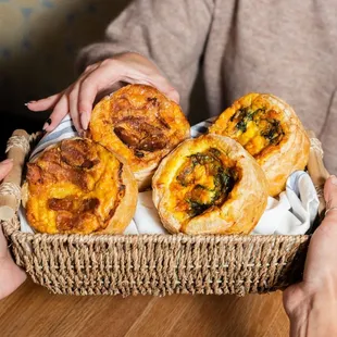 Person holding basket with quiches in it.