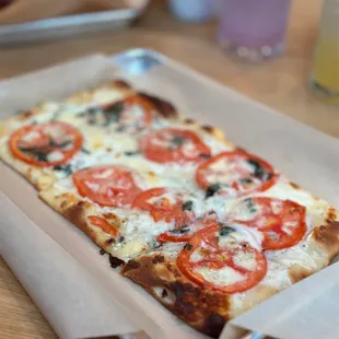 a square pizza with tomatoes and olives