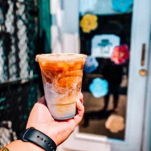 a hand holding a cup of iced coffee