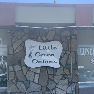 a stone wall with a sign that says little green onions