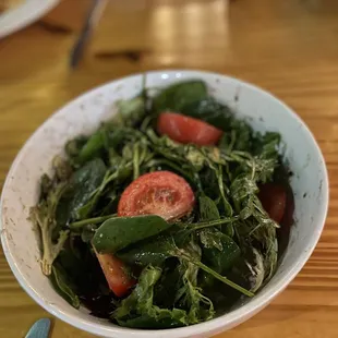 a bowl of salad on a wooden table