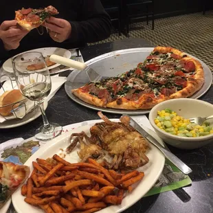 Partly eaten &quot;the Works&quot; pizza, soft shell crabs with sweet potato fries, side of succotash