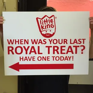 a woman holding a sign that says, when was your last royal treat? have one today