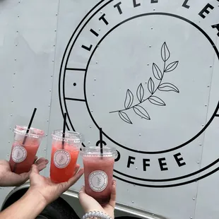 three people holding glasses of juice