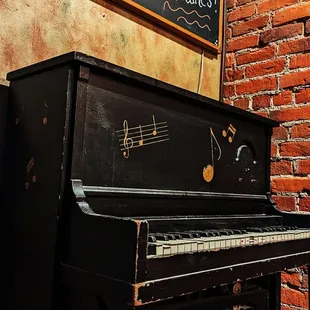 an old piano in front of a brick wall