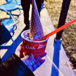 Space Junkie scoop in a to go cup with a side sugar cone