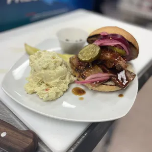 Brisket sandwich, with potato salad and pickled red onion with pickles.