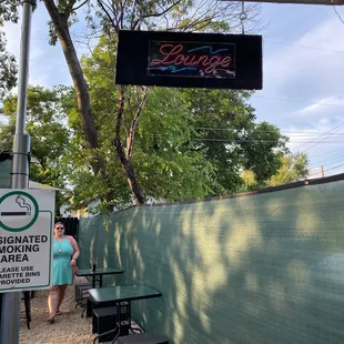 a woman standing under a neon sign