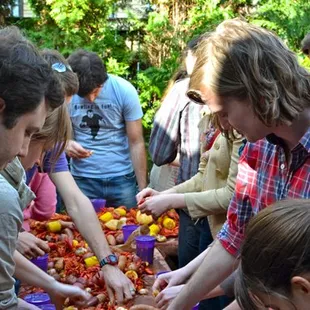 a group of people gathering around a table full of fruit