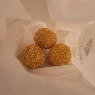 three sesame balls in a paper bag
