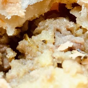 Close up of flaky meat pie crust and stuffing.