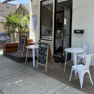 a sidewalk cafe with tables and chairs