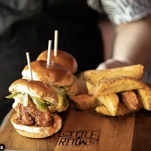 two burgers and fries on a cutting board