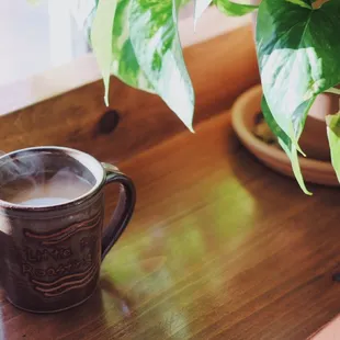 Hot cup of coffee and plants on window bar