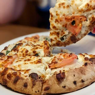 a person taking a slice of pizza