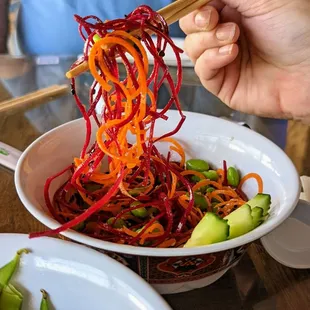 a person holding chopsticks over a bowl of ramen noodles
