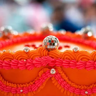 Close up of Orange &amp; pink vintage-style, disco wedding cake made by Little Sugar Crumb Sweets - says Just Hitched