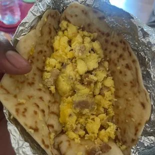 a person holding a breakfast burrito