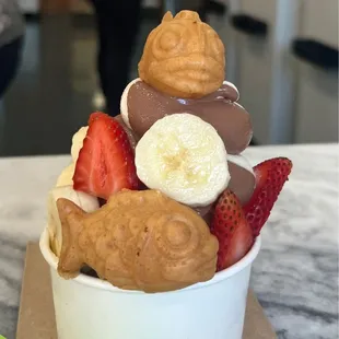 a bowl of ice cream with strawberries, bananas, and peanut butter
