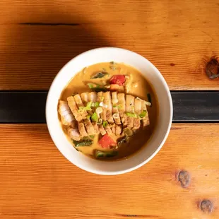 A bowl of delicious with pork belly and fresh veggies.