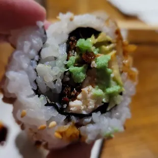 a hand holding a piece of sushi