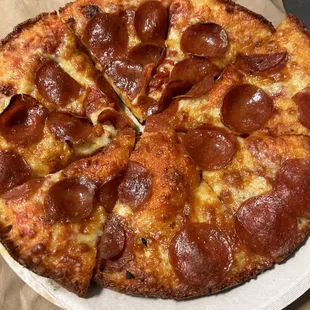 a pepperoni pizza on a paper plate