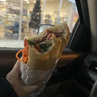 a person holding a sandwich in a car