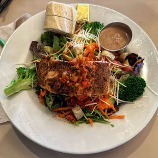 Veggie salad with grilled salmon and dressing on the side. No onions
