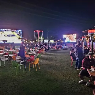 a crowd of people sitting at tables in a park at night