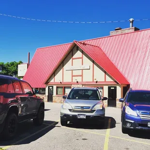 three cars parked in front of a small building