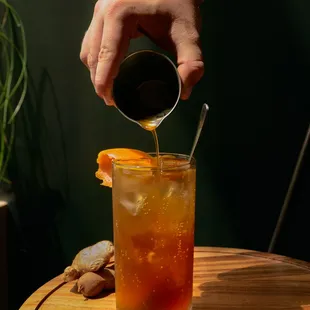 a person pouring a drink into a glass