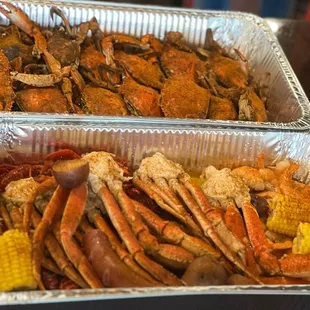 two trays of crab legs and corn on the cob