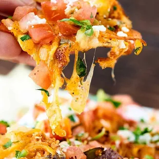 a hand holding a slice of pizza