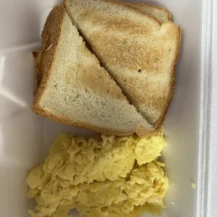 a sandwich and scrambled eggs in a styrofoam container