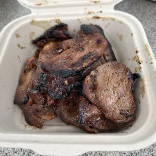 a close up of a piece of meat in a styrofoam container