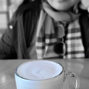 a woman sitting at a table with a cup of coffee