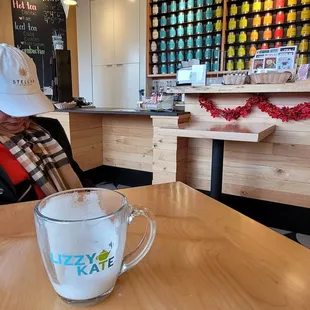 a woman sitting at a table with a cup of coffee