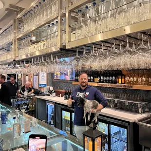 a man standing at a bar with a cat on his shoulder