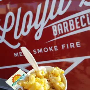 a hand holding a bowl of macaroni and cheese