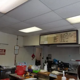 a restaurant counter with a menu above it