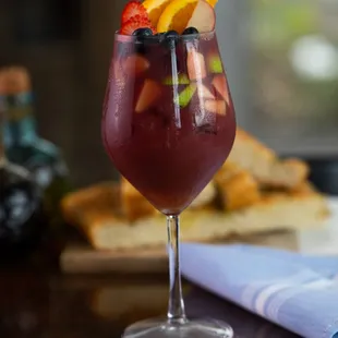 a glass of wine with fruit garnish