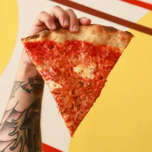 a hand holding a slice of pizza