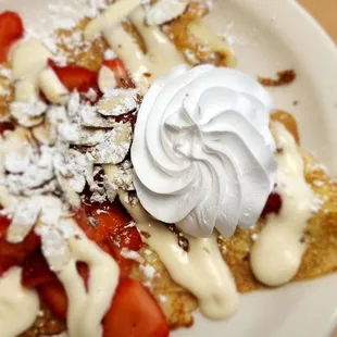 a plate of french toast with strawberries and whipped cream