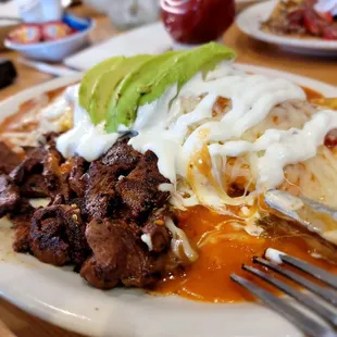 Omelet chilaquiles with Asada, sour cream, avocado, caramelized onions, red sauce (a little on the spicy end for a chicken like me)