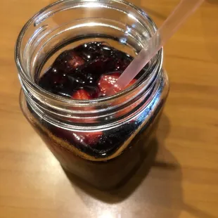 a jar of fruit with a straw