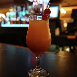 a cocktail in a glass with a straw and a cherry garnish