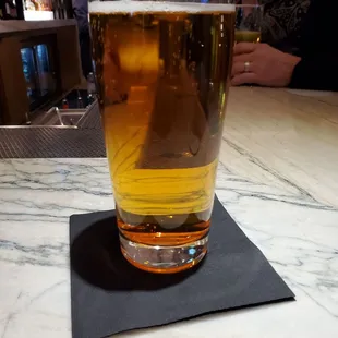 a glass of beer on a napkin