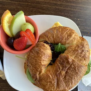 a croissant sandwich and fruit salad